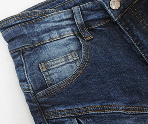 Detail of dark blue motorcycle jeans featuring contrast stitching and engraved metal button