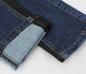 Detail of blue denim motorcycle jeans featuring side webbing and contrast yellow stitching