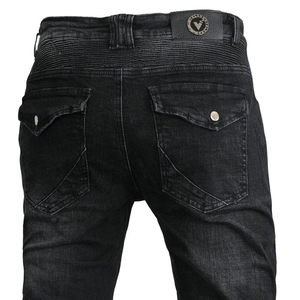 Detail of motorcycle jeans with leather patch, metal logo, and pleated waist design
