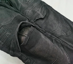 Detail of motorcycle jeans with accordion knee panels and removable protective armor inserts