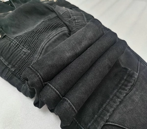 Detail of black biker jeans showing ribbed accordion panels and heavy denim texture