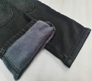 Detail of winter motorcycle jeans showing black denim with thick warm fleece lining texture