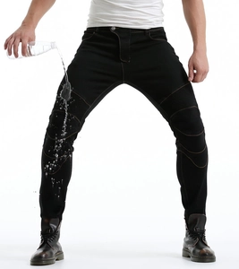 Close-up of black motorcycle jeans showing waterproof fabric with water droplets on the surface