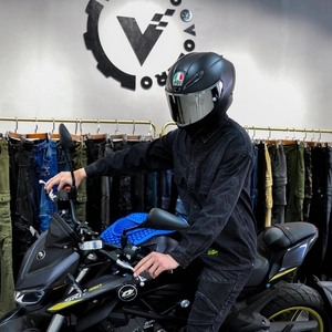 Nahaufnahme eines mattschwarzen Motorradhelms mit silbernem Visier und schwarzer Jeansjacke