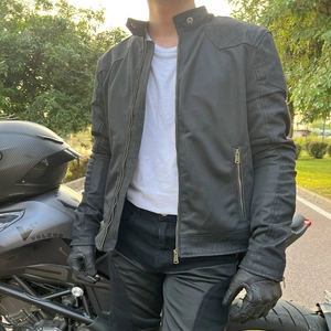 Detail of a black breathable mesh motorcycle jacket with bronze zippers and stand collar
