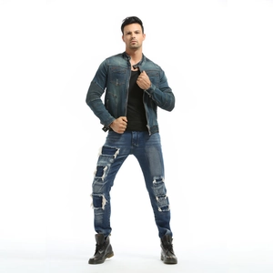 Full body view of a male model wearing a vintage washed denim motorcycle jacket and slim jeans