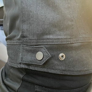 Close-up of motorcycle jacket showing mesh panels, denim fabric and adjustable waist snap