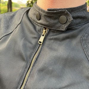 Detail of breathable mesh fabric and bronze metal zipper on motorcycle riding jacket