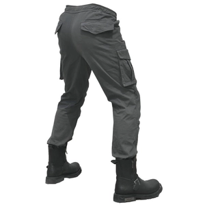 Dettaglio dei pantaloni cargo da moto grigio scuro con multitasche e stivali