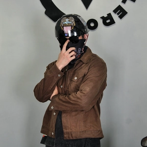Close-up of retro brown waxed cotton motorcycle jacket with vintage biker gear and helmet