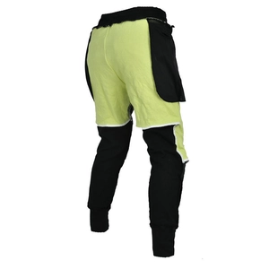 Detail of neon green motorcycle riding pants with reinforced stitching and ribbed ankle cuffs