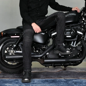 Close-up of black motorcycle jeans worn on a bike showing stretch fit and knee pleats