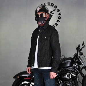 Men's retro waxed black motorcycle jacket shown with bike in minimalist studio setting
