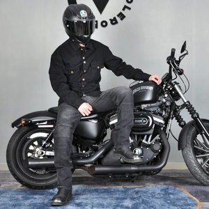 Detail of male biker protective gear featuring a black work shirt and denim motorcycle pants