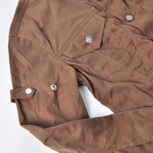 Detail of brown wax-coated motorcycle jacket with metal snap buttons and utility pockets