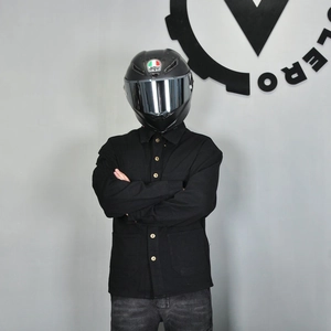 Detail of a black heavy cotton motorcycle shirt jacket with a carbon fiber helmet
