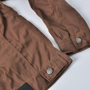 Detail view of the deep brown motorcycle jacket showing metal buttons and canvas texture