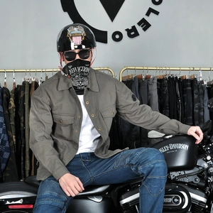 Detail of olive green vintage motorcycle jacket with chest pockets on a rider