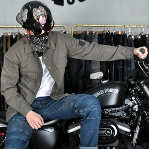 Detail of army green motorcycle jacket featuring chest pockets and classic arm patch