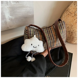 Details der Vintage-Tasche mit Hahnentrittmuster, Lederriemen und Plüsch-Anhänger