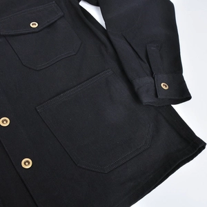Detail of heavy duty black cotton twill jacket with workwear pockets and brass buttons