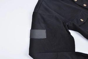 Detail of black motorcycle jacket sleeve with leather patch and golden metal button