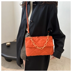 Détail d'un sac matelassé orange avec chaîne en résine et vue latérale sur le mannequin