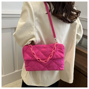 Détail du sac matelassé fuchsia avec chaîne décorative sur un mannequin en veste velours