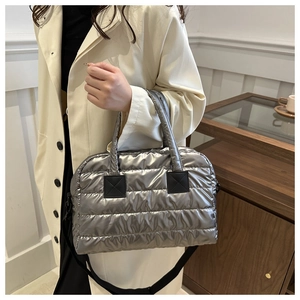 Detail van zilveren metallic gewatteerde tas met verstelbare zwarte schouderriem en textuur