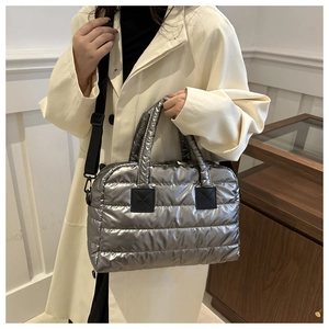 Detail van metallic zilveren gewatteerde Boston tas met zwarte riemen en zachte textuur