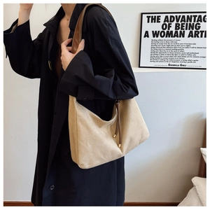Grote beige draagtas met bruine banden en matte textuur gedragen door een model