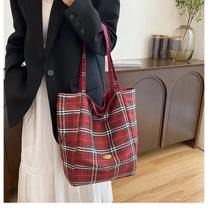 Classic tartan canvas tote bag with red strap and gold logo plate shown on model