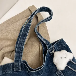 Detail of denim bag handle with white stitching and plush cloud charm accessory