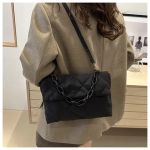 Détail du sac bandoulière matelassé noir avec grosse chaîne porté par un mannequin