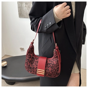 Detalle de bolso hobo con estampado de leopardo rojo y hebilla dorada en una modelo