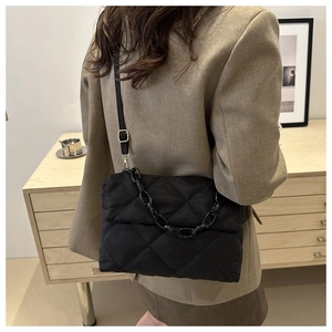Détail du sac matelassé noir en nylon avec chaîne décorative et bandoulière réglable