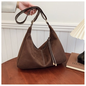 Detail van donkerbruine matte hobo-tas met witte stiksels en lange kwast aan de rits