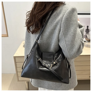 Vue latérale d'un sac cabas en cuir noir mat avec sangles décoratives sur un mannequin