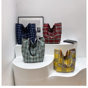 Multiple checkered tote bags in various colors displayed on a minimalist white platform