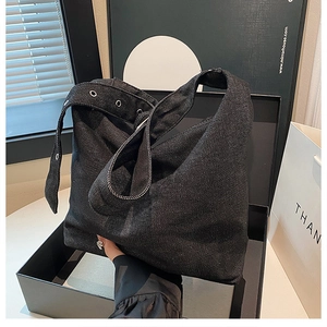 Détail du sac hobo en jean noir avec large bandoulière et œillets métalliques