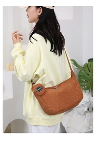 Detailed close-up of brown corduroy crossbody bag texture with matching round coin purse pouch