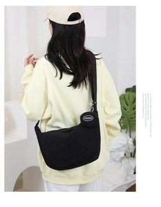 Model view of black corduroy crossbody bag with adjustable strap and fashion logo
