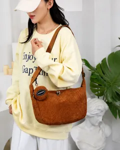 Detail view of caramel corduroy crossbody bag with adjustable strap and coin purse charm