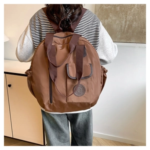 Dettaglio di un grande zaino in nylon marrone con logo vintage e tasche laterali a coulisse