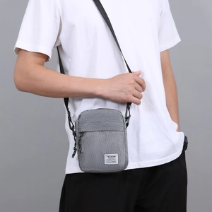 Borsa a tracolla da uomo in nylon grigio con tracolla regolabile indossata da un modello