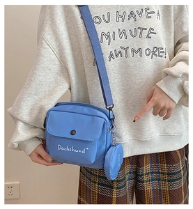 Blue nylon crossbody bag detail with adjustable strap and mini coin pouch accessory