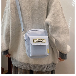 Vista trasera de un mini bolso bandolera azul claro con letras y jersey gris de gran tamaño