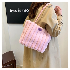 Détail du sac cabas en peluche rose à rayures verticales porté à l'épaule pour femme