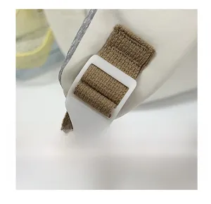 Macro detail of adjustable white buckle and woven nylon strap on a beige backpack