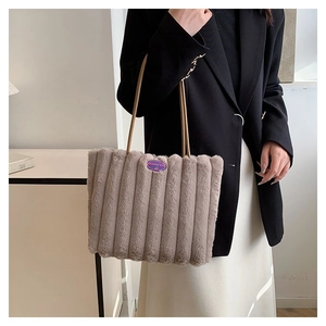 Détail d'un sac cabas en peluche avec rayures verticales et emblème tendance